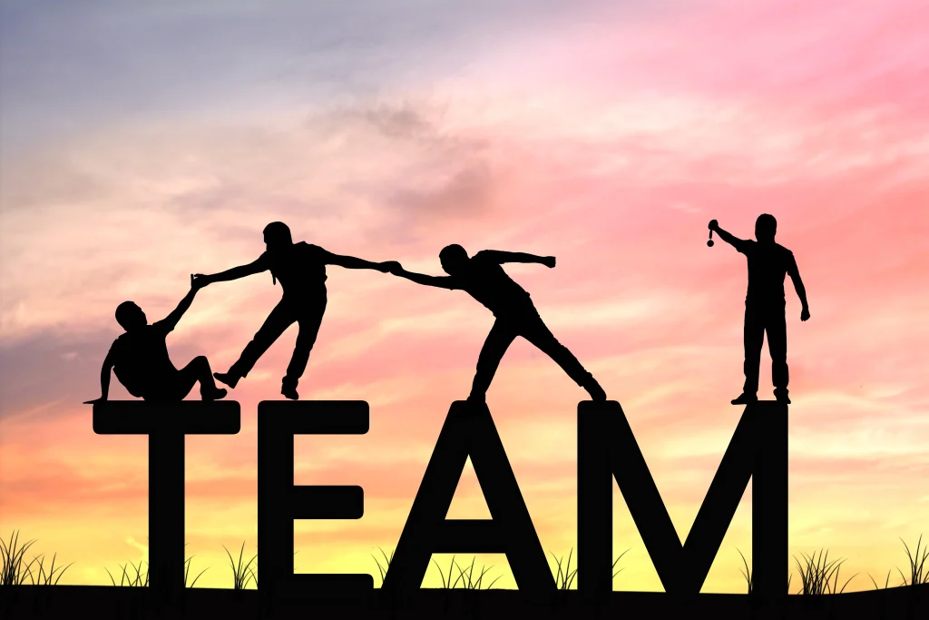 Illustration de team building : des silhouettes s’entraident en formant le mot TEAM