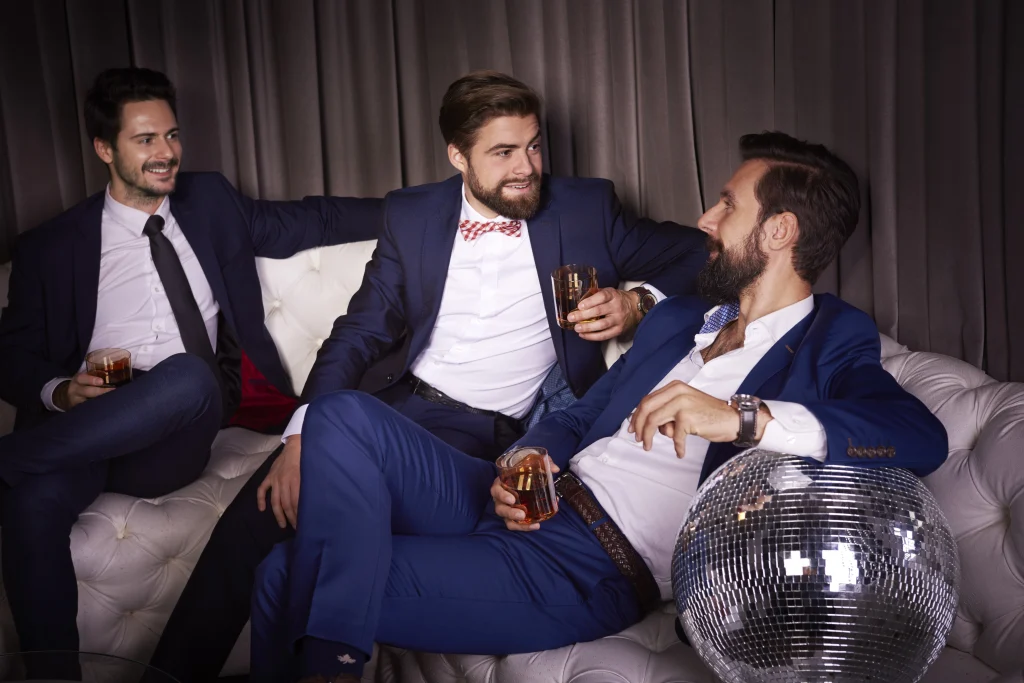 Groupe d’amis élégants en costume profitant d’une soirée chic autour de verres lors d’un EVG à Deauville.