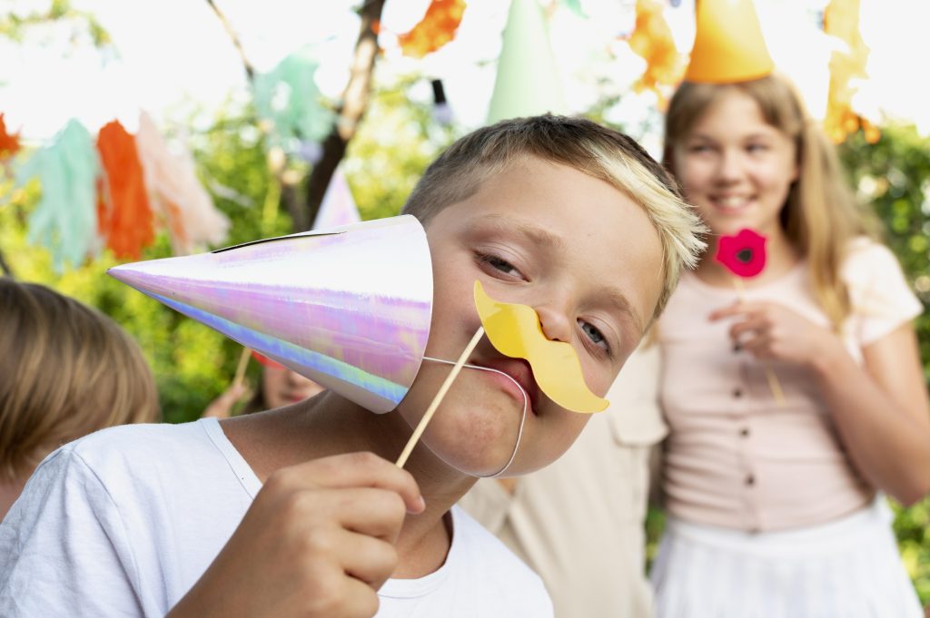 Animation pour enfants lors d’un anniversaire sportif Enfants portant des chapeaux et accessoires festifs, s’amusant ensemble lors d’un anniversaire sportif en plein air.