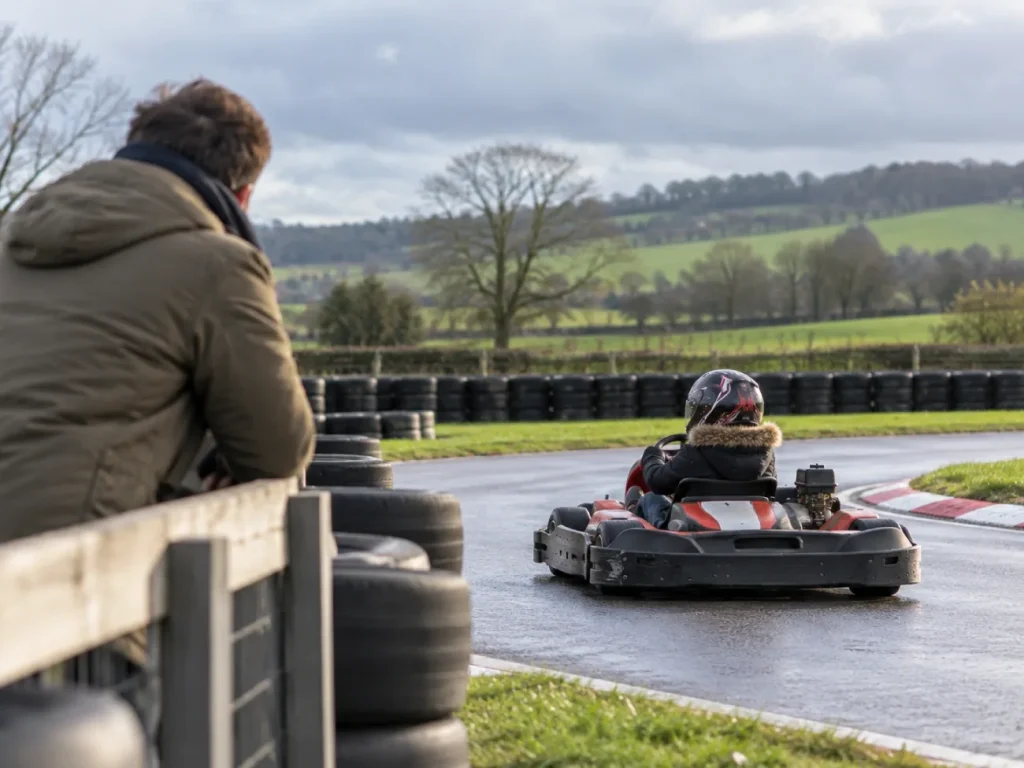Enfant en karting sur une piste extérieure sous le regard de son parent